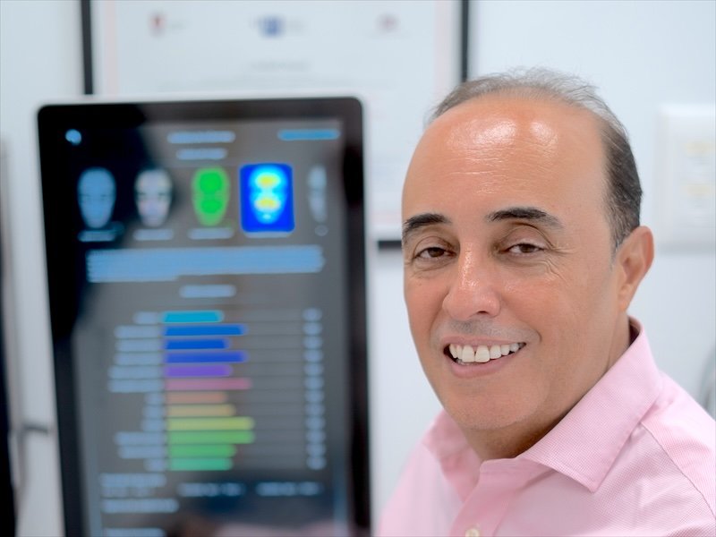 Dr. Oulkadi junto a la pantalla del analizador facial con el que realiza el diagnóstico de la piel