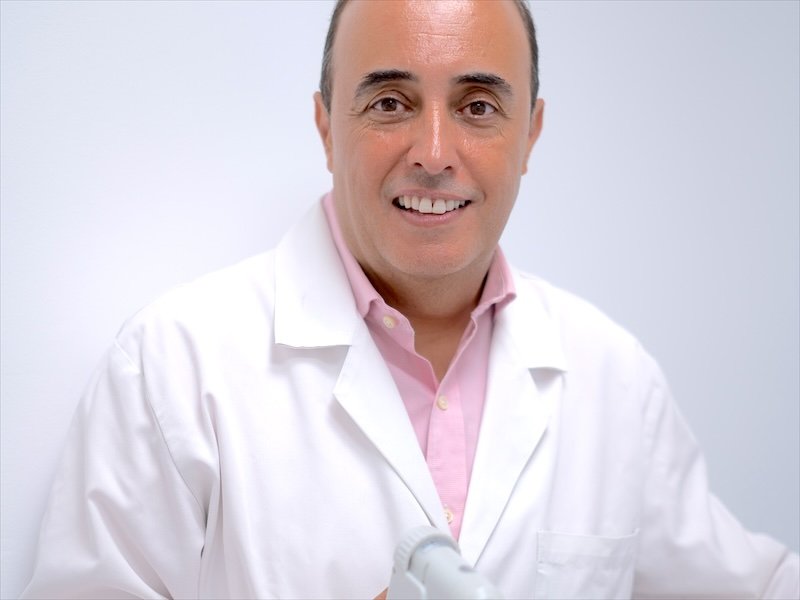 Dr. Oulkadi con bata blanca en la sala de tratamientos de su clínica